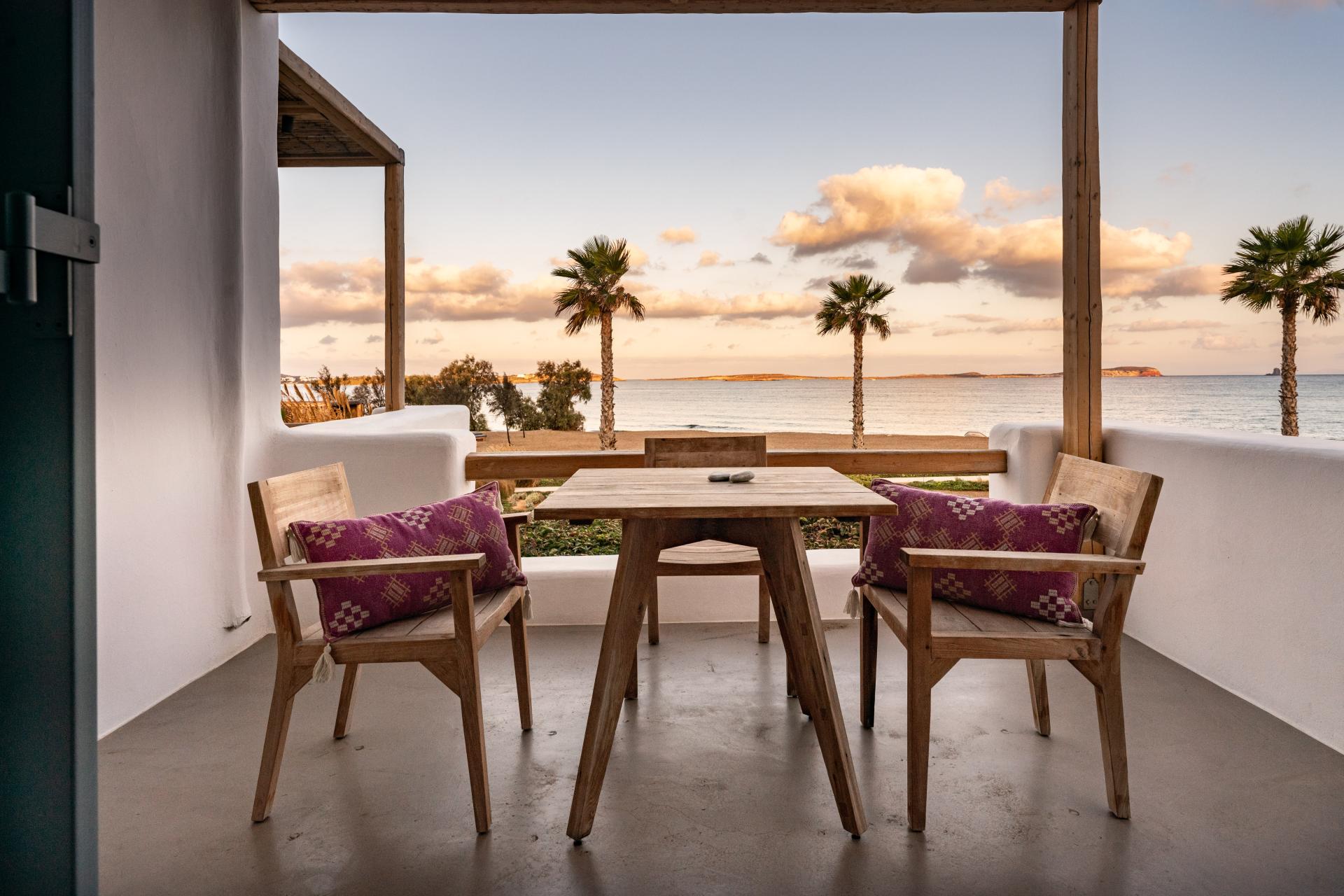 A table and three chairs in the terrace and the sea in the background